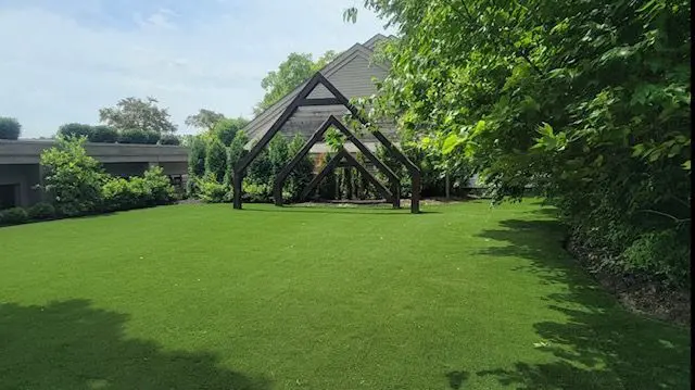 A large green lawn with trees and buildings in the background.