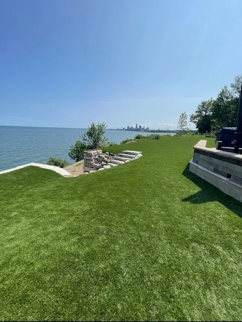 A view of the water from a house with grass on it.