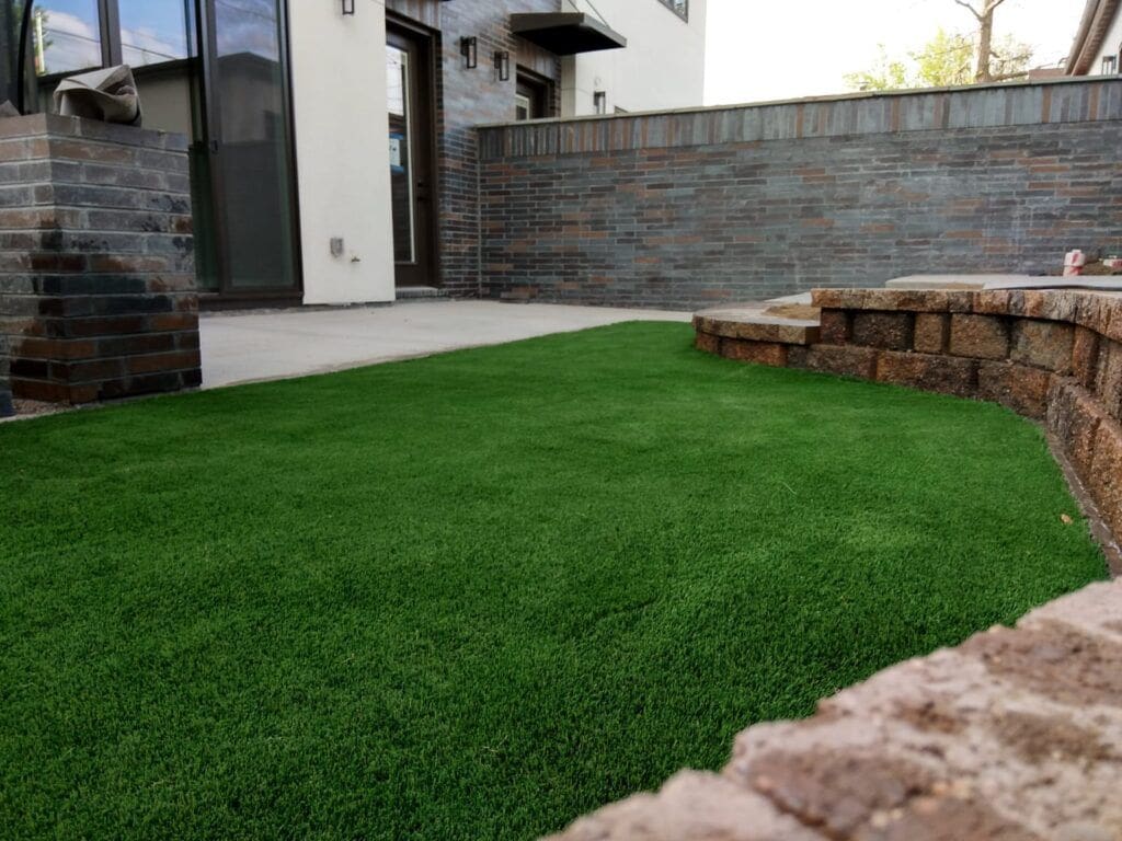A backyard with grass and brick walls.